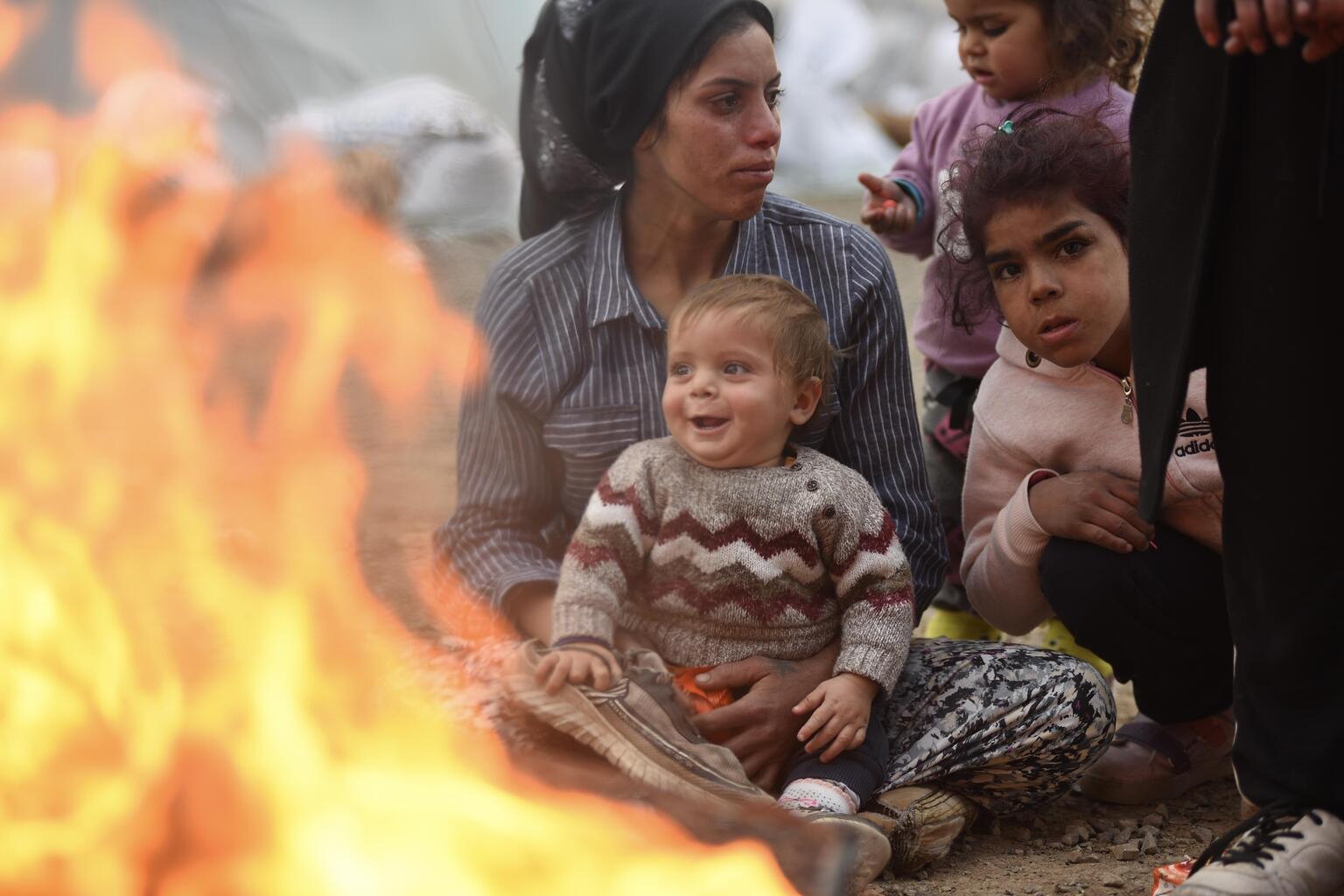 Družina iz Turčije se greje ob ognju pred šotori, v začasnem taborišču, kjer so nastanjene žrtve potresov. © UNICEF/UN0780742/Ölçer