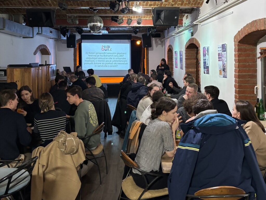 Poln MC Patriot in zbrani obrazi ekip med reševanjem vprašanj zadnjega pub kviza v letu 2025.