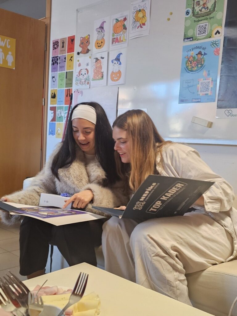 Dve dekleti sedta na kavču in gledata dokumnet - potrdilo o udeležbi