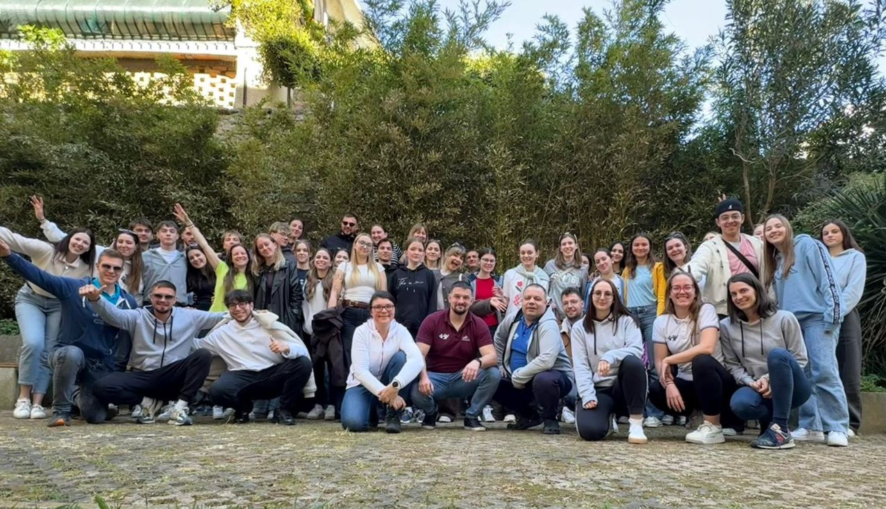 Vzgojitelji-animatorji in pedagoški vodje stojijo v atriju pri gimnaziji Piran in mahajo v pozdrav.